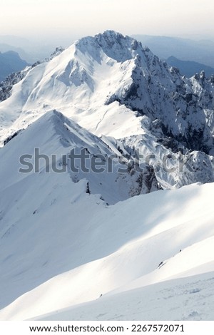 The snow-capped mountain stands tall against a clear blue sky, its jagged peaks and pristine snow reflecting the beauty and power of nature Royalty-Free Stock Photo #2267572071