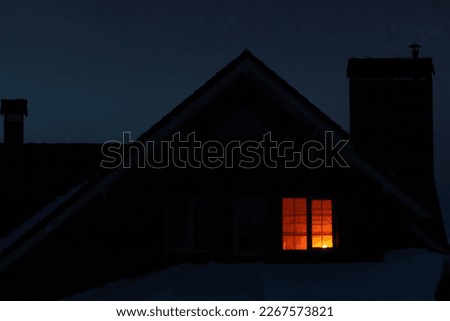 The light is on in the window of a private house.