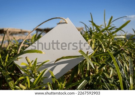 green leaves with tropical blue sea and a white hanging picture sign with empty free space for template or blank copy area