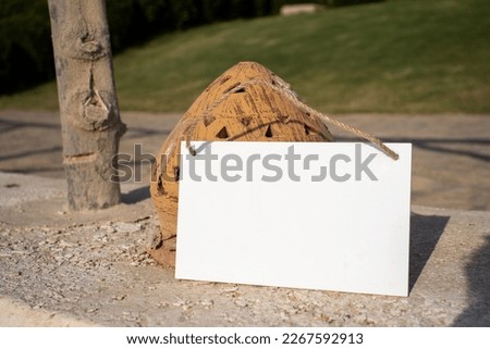 a white hanging picture sign next to a path light cover with empty free space for template or blank copy area