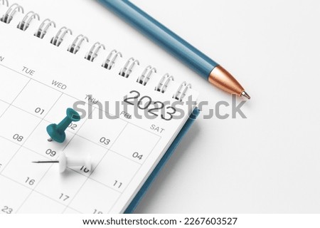 Scheduling and planning concept, calendar with blue pin and pen on white table, closeup