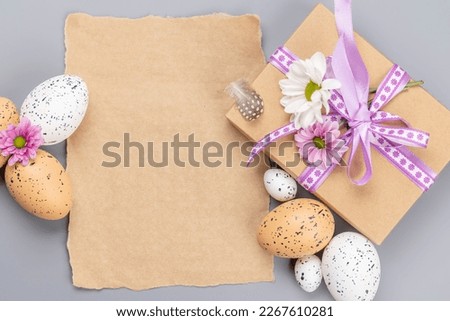 Gift box, Easter eggs and flowers on a gray background with space for your greetings. Flat lay