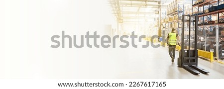 Storehouse employee in uniform working on forklift in modern automatic warehouse. Boxes are on the shelves of the warehouse. Warehousing, machinery concept. Logistics in stock. Royalty-Free Stock Photo #2267617165