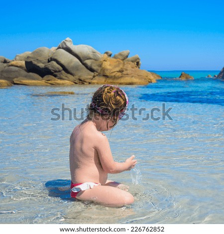 Cute little girl relaxing on tropical sea clean water, blue sky and reef in background