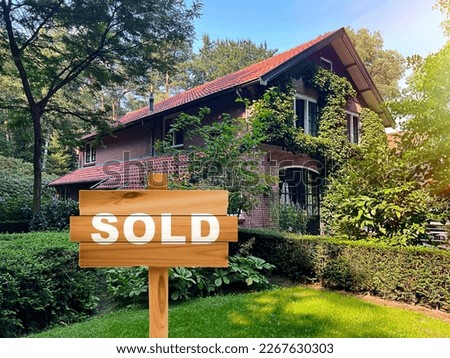 Wooden Sold sign near beautiful house outdoors