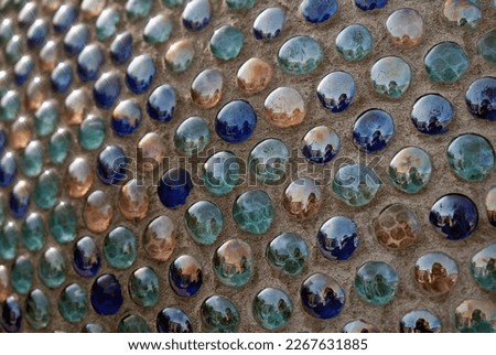 Closeup of mosaic background of round glass blue turquoise balls in wall