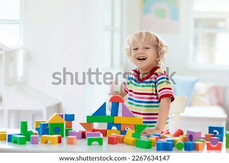 Kid playing with colorful toy blocks. Little boy building tower of block toys. Educational and creative toys and games for young children. Baby in white bedroom with rainbow bricks. Child at home. Royalty-Free Stock Photo #2267634147