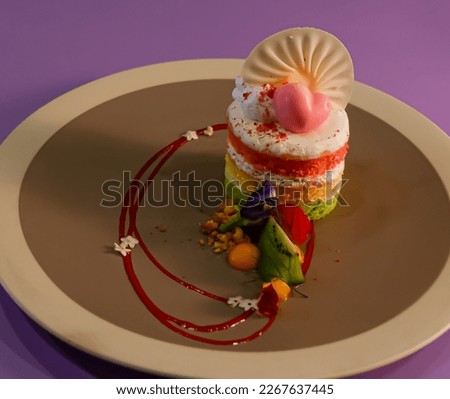 3 layer cake, green, yellow and red, decorated with heart and fan-shaped sweets, and a piece of kiwi fruit, in a restaurant