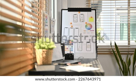 Creative office with laptop, stationery and wireframe sketches of screens for mobile application on a flip board