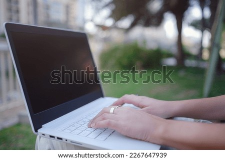 Female hands on laptop, woman types on keyboard sitting in park. Working outside and freelance concept