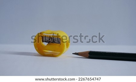 a yellow pencil sharpener with a green pencil