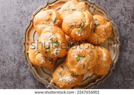 Homemade Buttery Garlic Knot Bread with Parsley and Parmesan cheese and dried greens closeup on the plate on the table. Horizontal top view from above
 Royalty-Free Stock Photo #2267656001