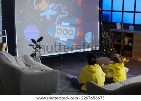 Little boy and his sister in 3D glasses watching cartoons on projector screen at home Royalty-Free Stock Photo #2267656675