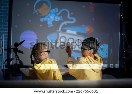 Little children in 3D glasses with popcorn watching cartoons on projector screen at home Royalty-Free Stock Photo #2267656681