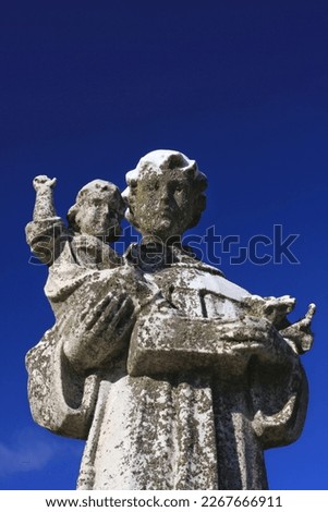 A natural stone statue of a young Saint Joseph carrying the baby Jesus.