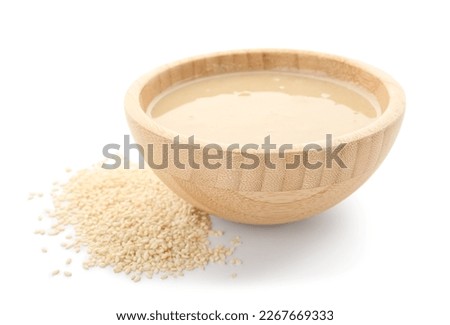 Wooden bowl with tasty tahini and sesame seeds on white background Royalty-Free Stock Photo #2267669333