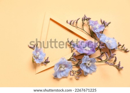 Blank triangular frame and beautiful delphinium flowers on orange background