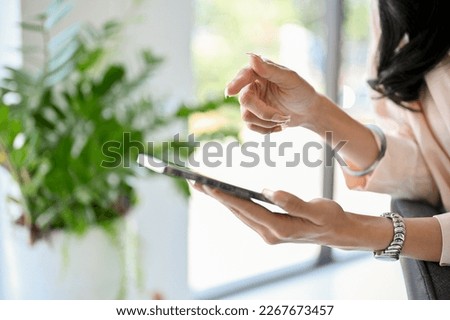Cropped and side view image of a businesswoman or female using her smartphone, finger pointing on smartphone screen.