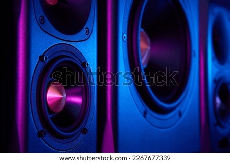 Two sound speakers and subwoofer on dark background with neon lights. Set for listening music. Audio equipment Royalty-Free Stock Photo #2267677339