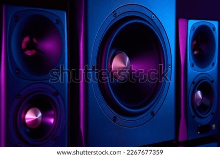 Two sound speakers and subwoofer on dark background with neon lights. Set for listening music. Audio equipment Royalty-Free Stock Photo #2267677359