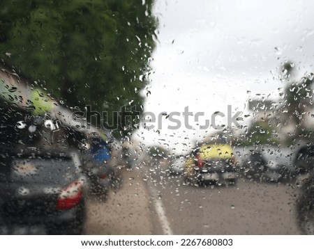 blurry image of a car glass exposed to rain on the side of the road