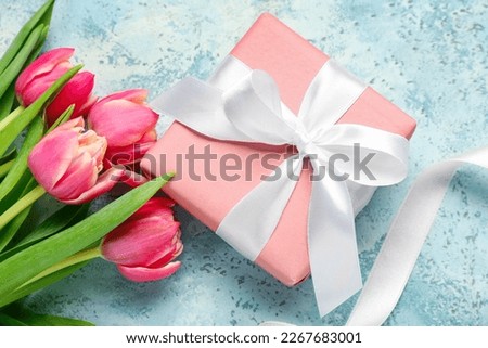 Gift box, ribbon and beautiful tulip flowers on grunge background. Hello spring