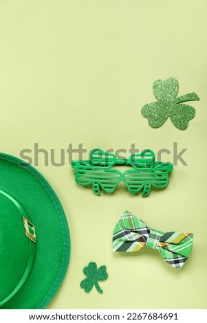 Leprechaun hat with eyeglasses, bow and paper clover on green background. St. Patrick's Day celebration