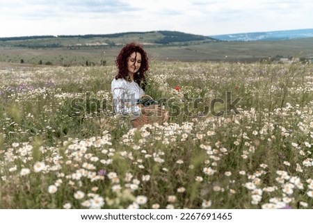 Chamomile woman. Happy curly woman in a chamomile field, dressed in a white dress.