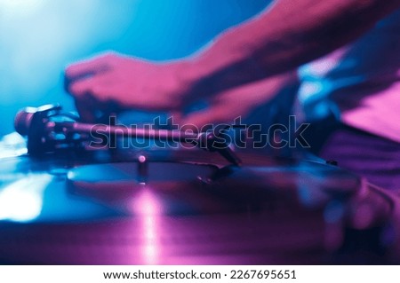 Club DJ paying music with vinyl records and turn table. Disc jockey mixing musical tracks on party in nightclub, focus on turntables needle
