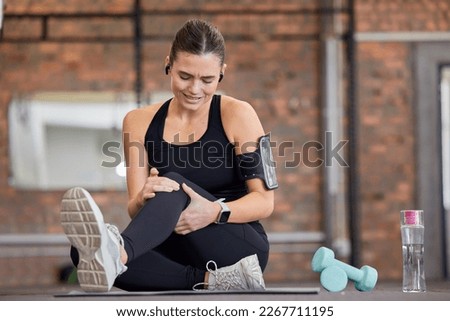 Knee pain, fitness and woman with injury in gym after accident, workout or training. Sports, health and young female athlete with fibromyalgia, inflammation or arthritis, tendinitis or painful legs. Royalty-Free Stock Photo #2267711195