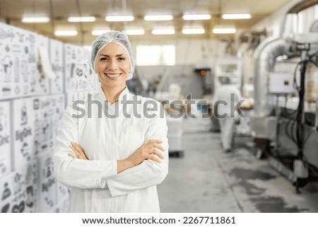 Portrait of a food factory worker proudly standing in facility and smiling at the camera.