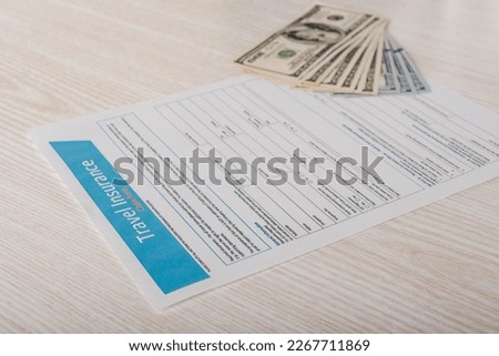 Travel insurance application form and dollar banknotes on table