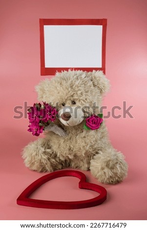 Stock image that can be used for any occasion.  Depicting a cute teddy bear with a bouquet of flowers and a blank sign with a heart in the foreground.