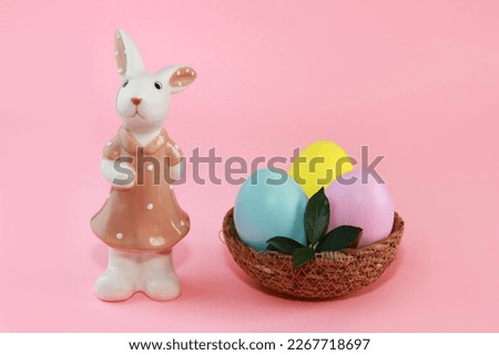 Ceramic figurine of a bunny in a dress and colorful Easter eggs in a plate