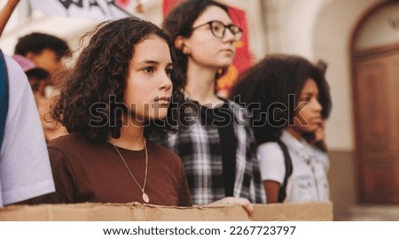 Group of multicultural protestors marching against war and violence in the streets. Youth activists raising anti-war posters during a peace and human rights demonstration. Royalty-Free Stock Photo #2267723797