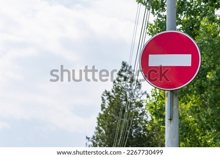 A no entry sign, or brick, prohibits the entry of any vehicle in a direction that overlaps this road sign. Background with copy space Royalty-Free Stock Photo #2267730499