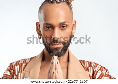 Patience, calmness and meditation concept. Peaceful relieved bearded young man practices yoga exercise, keeps hands in zen gesture, closes eyes, isolated on white background, controls his emotions