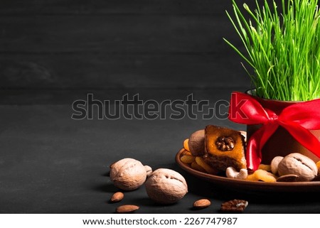 Novruz setting table decoration, wheat grass, baklava pastry and nuts on dark background. Nowruz arabic holiday, new year spring celebration, copy space.