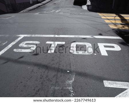 white Stop sign letters on a grey street in the Caribbean Royalty-Free Stock Photo #2267749613