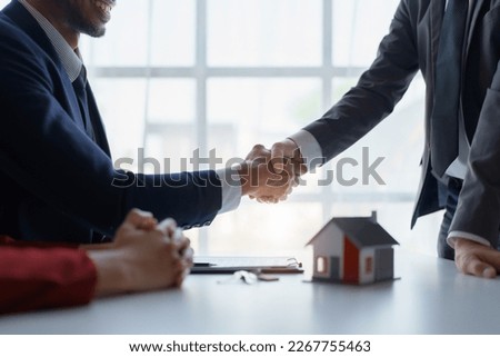 Asian real estate agent shaking hands handing over house and keys to his client's house after client sign contract