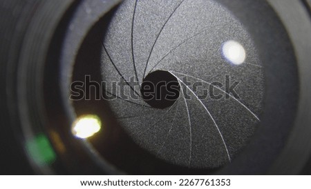 Front close detail of camera lens diaphragm blades smoothly opening