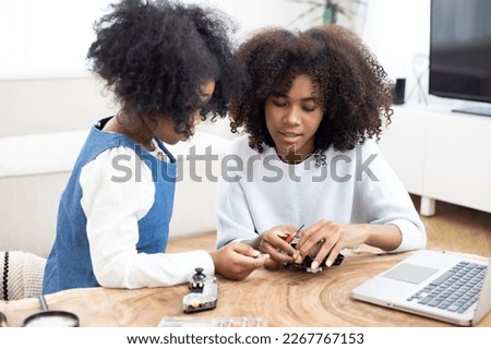 Mother and daughter programming and building a scientific robotics project. STEM-education. Programing robot vehicle in living room computer coding at home.