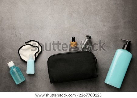 Preparation for spa. Compact toiletry bag with different cosmetic products on grey textured background, flat lay. Space for text Royalty-Free Stock Photo #2267780125