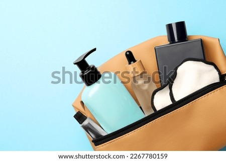 Preparation for spa. Compact toiletry bag with different cosmetic products on light blue background, top view. Space for text Royalty-Free Stock Photo #2267780159