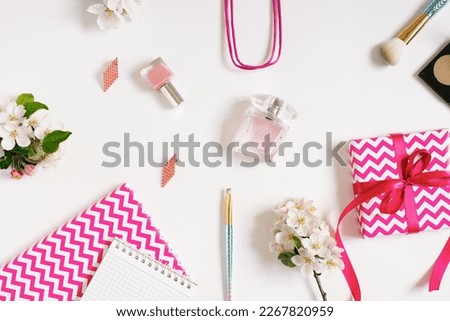 Concept of a beauty blog. Accessories for women's makeup and delicate apple blossoms on a white background. Flat apartment, top view, women's desk, workplace with notebooks in pink