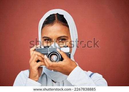 Photography, portrait of muslim woman holding camera and mockup with smile isolated on red background. Creative professional lifestyle photographer in hijab, hobby or career taking photo in studio.