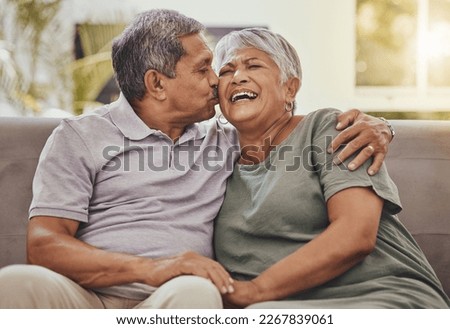 Happy, senior couple and kiss of elderly woman and man laughing with happiness on a sofa. Living room, couch and marriage support of people in retirement with love and joy together in a house lounge