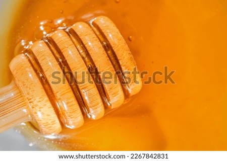 Honey with a dipper of honey lies on a white saucer, close-up, top view. flat lay on natural bee products. Natural products from farms in Turkey