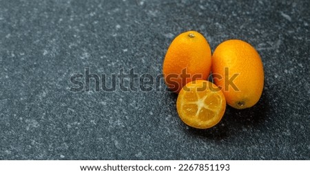 Citrus kumquat fruits on a dark background, organic food market. Long banner format. top view.