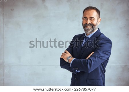 Portrait of a confident mature businessman working in a modern office. Mature cheerful executive businessman at workspace office. Portrait of smiling ceo at modern office workplace in suit 